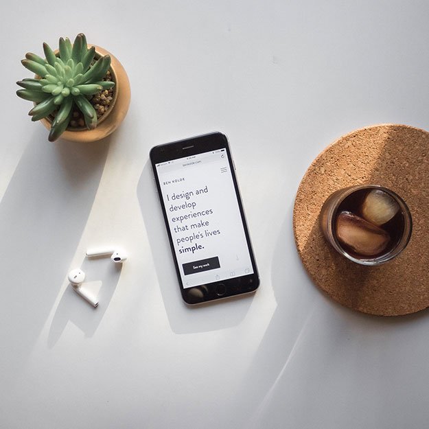 Phone sitting on a table between a plant and coffee cup